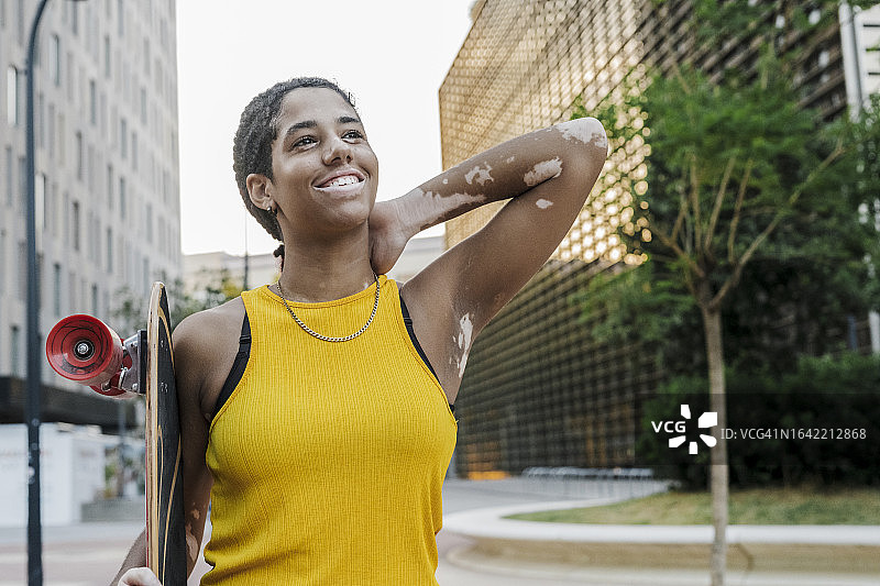 青少年女性手持滑板在城市中行走图片素材