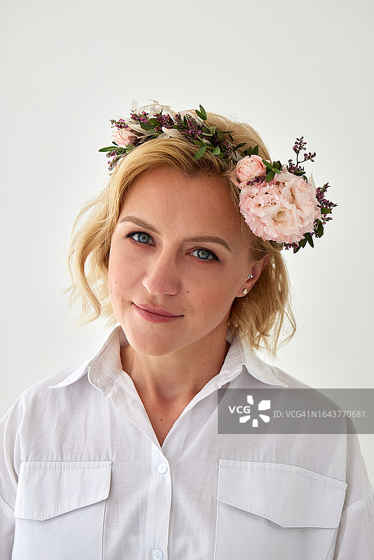戴着花环的年轻女子站在灰色墙壁旁图片素材