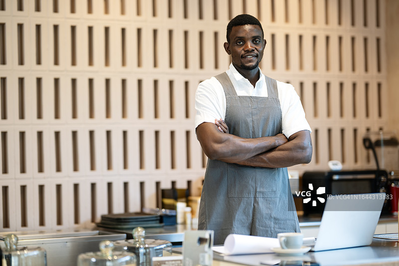 通过在线营销渠道扩大客户群。在柜台工作的非洲裔美国男店主或咖啡师，为他的咖啡馆感到自豪。企业主，小企业运营。图片素材