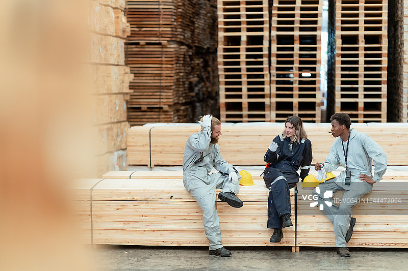 木材厂工人在大型仓库中休息交谈图片素材