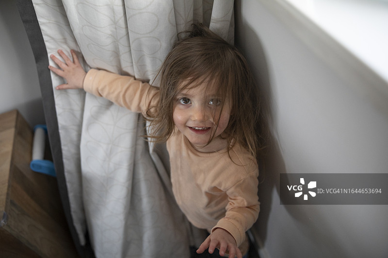 玩捉迷藏游戏，从客厅窗帘后面出现的儿童图片素材