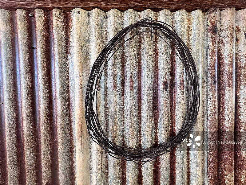 旧农场阴影下金属墙上的锈迹斑斑的铁丝图片素材