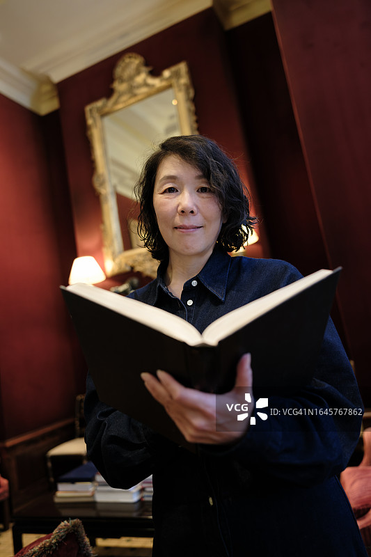 在家拿着书的微笑亚洲女人图片素材