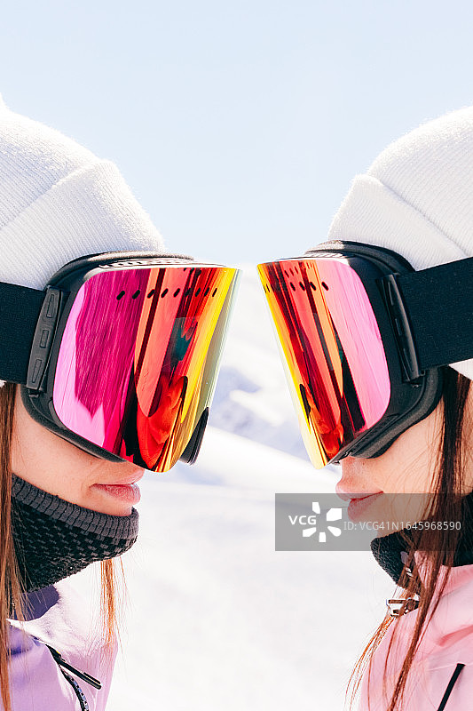 两位闺蜜滑雪者在阳光明媚的日子里戴着滑雪镜滑雪图片素材