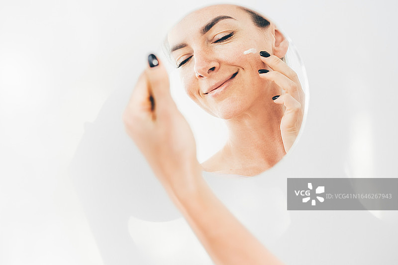 年轻女子用面霜滋润脸部图片素材