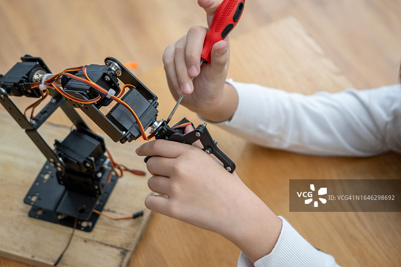 女孩用万用表检测机器人手臂电路板特写图片素材