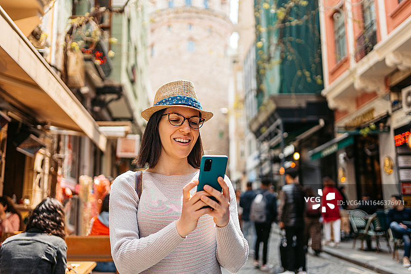 年轻女人在伊斯坦布尔加拉太塔前使用手机图片素材