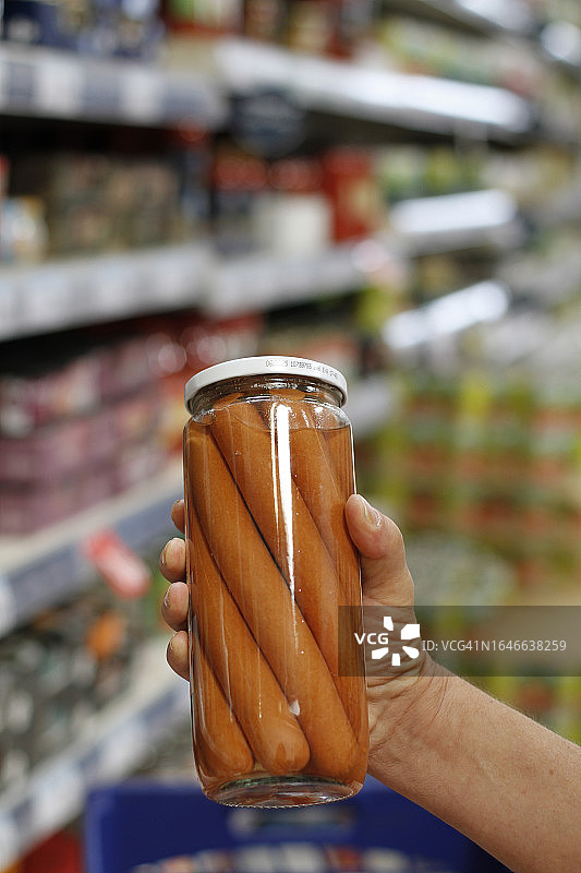 在超市拿着一罐香肠的男人图片素材