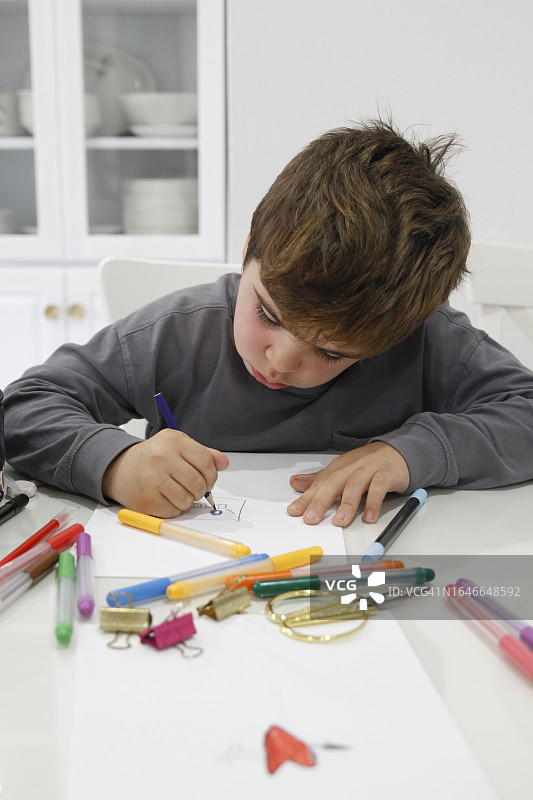 小男孩在家里的桌子上做手工图片素材