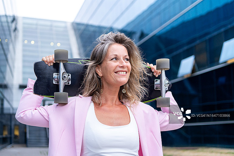 手持滑板的快乐休闲女商人肖像图片素材
