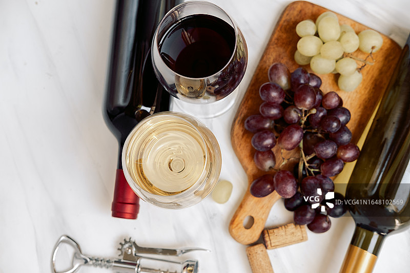 白桌上的法式白葡萄酒杯和意大利红葡萄酒杯，以及葡萄酒瓶和葡萄图片素材