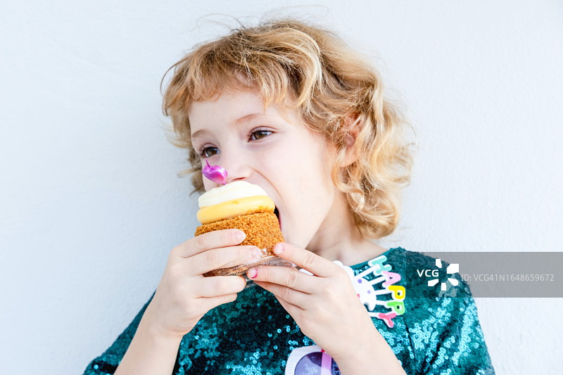 可爱的小女孩咬着她的生日蛋糕庆祝图片素材