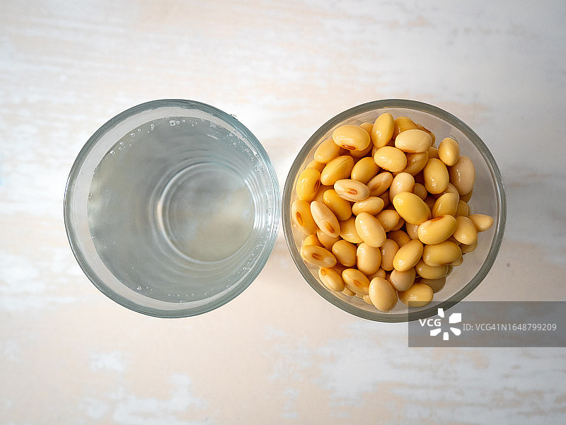 白色桌子上玻璃杯旁浸泡的黄豆图片素材