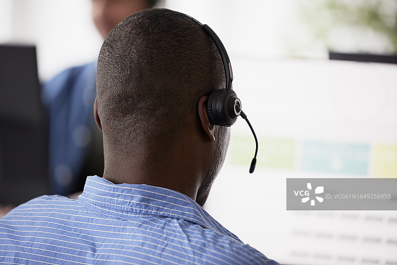 男子在办公室戴着耳机坐着的背影图片素材