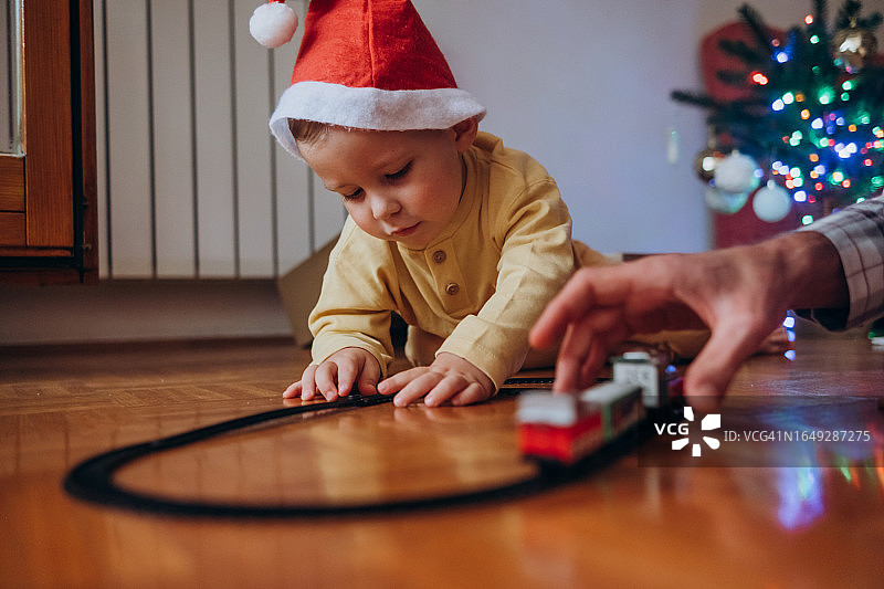 戴着圣诞帽玩玩具火车的可爱小男孩图片素材