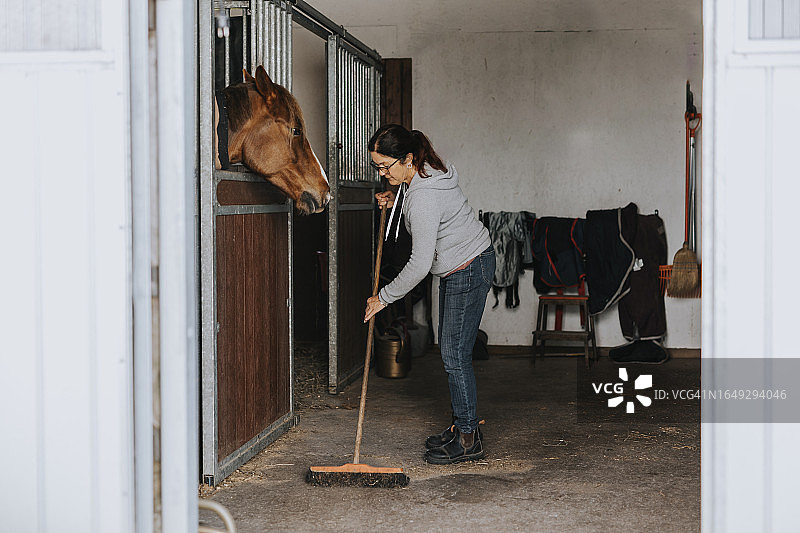 在马厩里扫地的女人图片素材