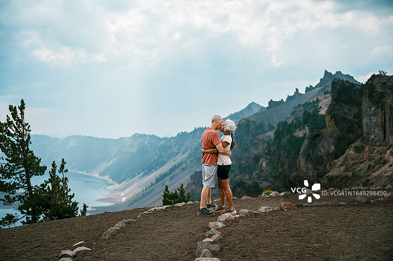 在山间徒步瞭望点接吻的充满活力的年长夫妇图片素材