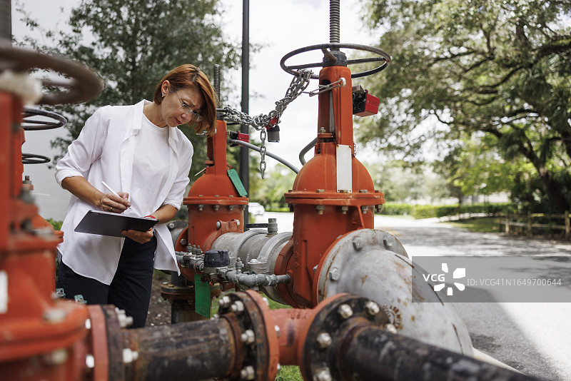 理赔员使用平板电脑检查户外管道和阀门图片素材