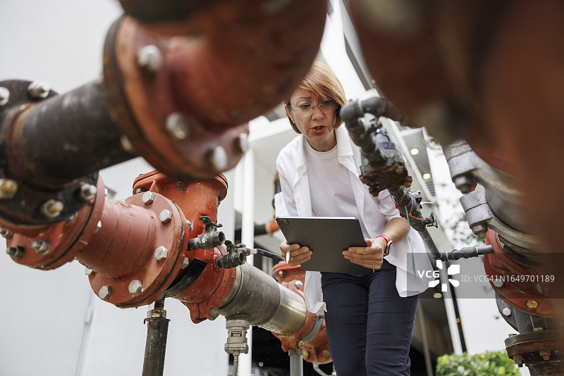 水利基础设施理赔评估：理赔员检查户外供水卫生设施的损坏影响，低角度拍摄图片素材
