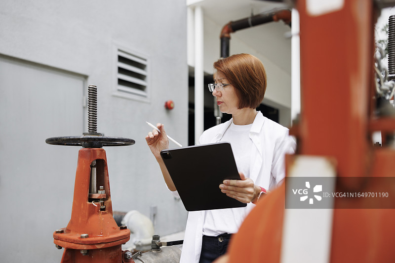 管道建设专业知识和腐蚀控制，戴眼镜的女人在户外调查对供水和卫生设施的损害和影响图片素材