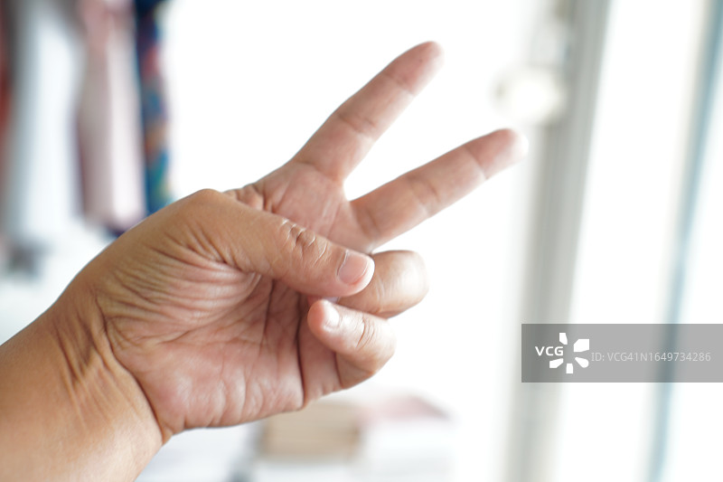 亚洲女性剪刀手势特写，胜利手势，白色背景图片素材