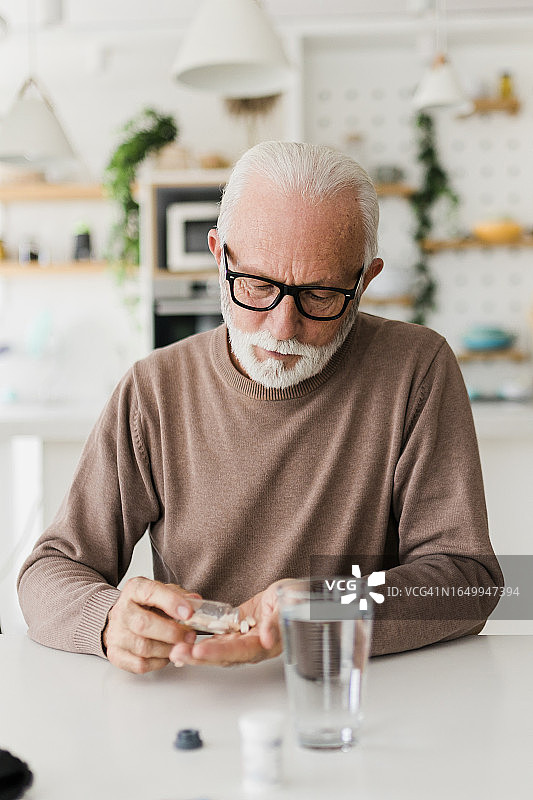 年长的男人在客厅服用止痛药缓解疾病症状图片素材