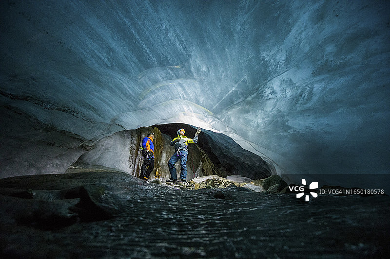 两个男人惊叹于融化冰川下的冰冻河流图片素材