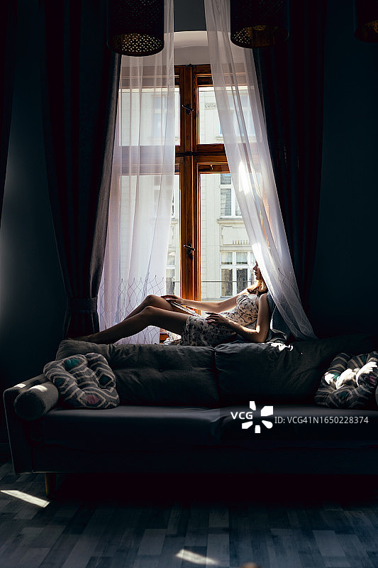 在公寓窗台上摆姿势的白裙女孩图片素材