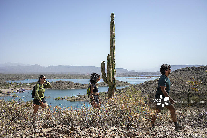 湖边沙漠山路上仙人柱旁的徒步者图片素材