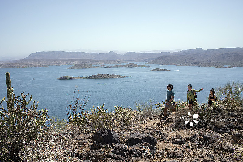 沙漠山间小路上的徒步旅行者，背景是湖泊图片素材