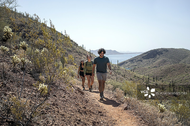 徒步者在丘陵小路上行走，背景是湖泊图片素材