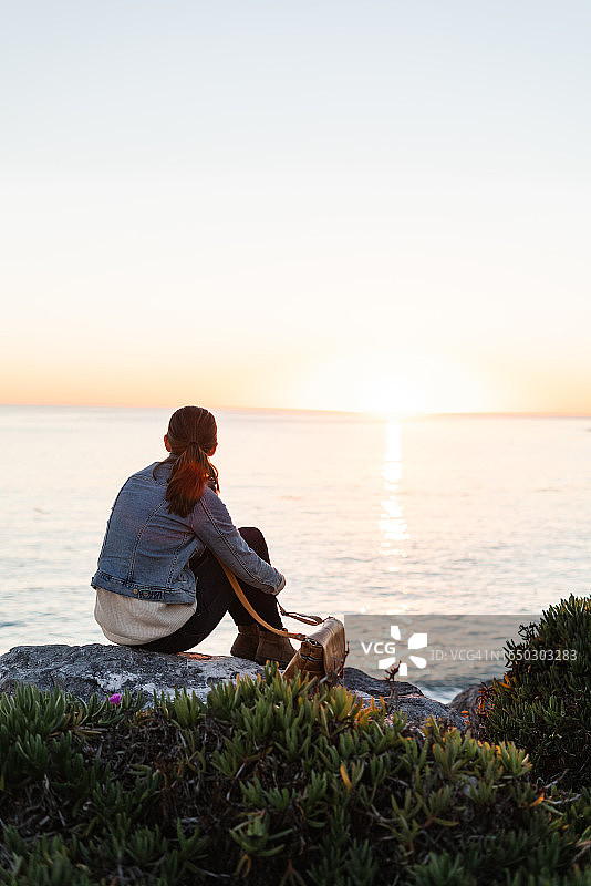 在岩石海洋海岸观看日落的女人图片素材