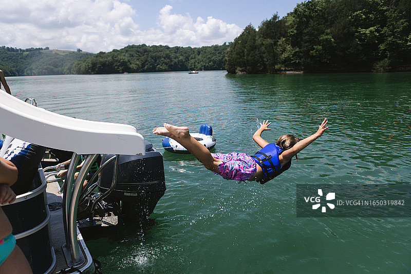 孩子从浮筒船滑梯上滑入湖中图片素材