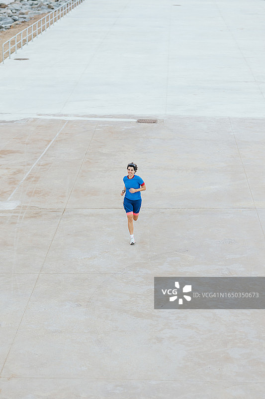 充满活力的女子在城市运动跑道上独自锻炼图片素材