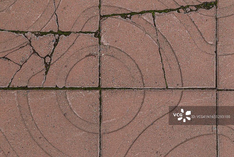 户外带有几何形状的破碎风化红色方形铺路石或砌块的特写，从上方观看图片素材