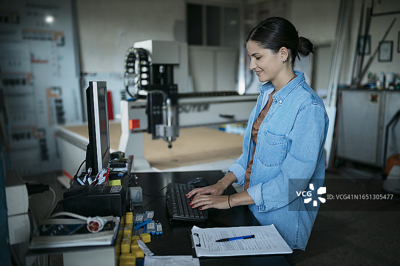 在标牌制作车间使用数控雕刻机电脑的女人图片素材