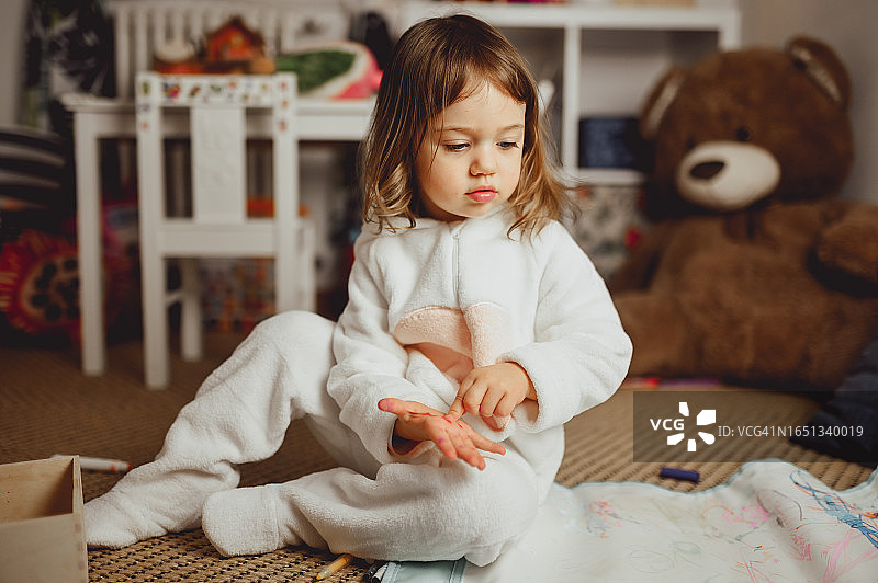 穿着睡衣坐在地板上的可爱幼儿女孩肖像图片素材