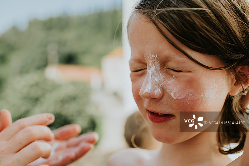 家长为孩子背部涂抹防晒霜图片素材