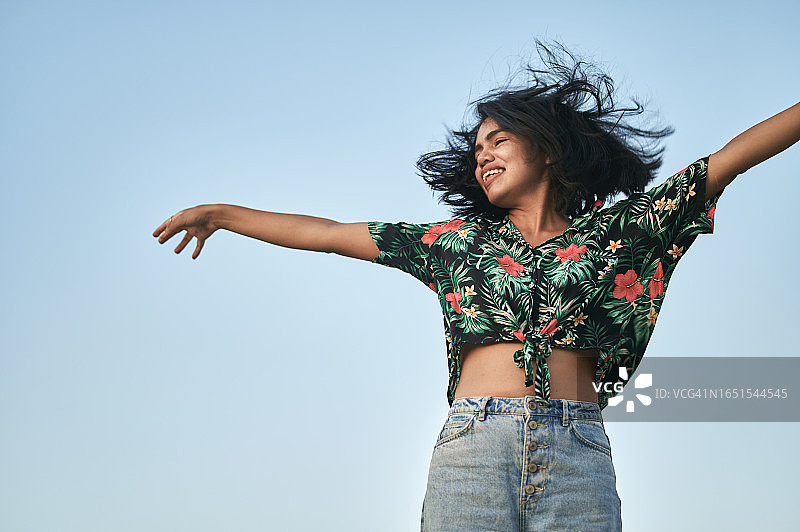 在蓝天下甩动头发的女子肖像图片素材