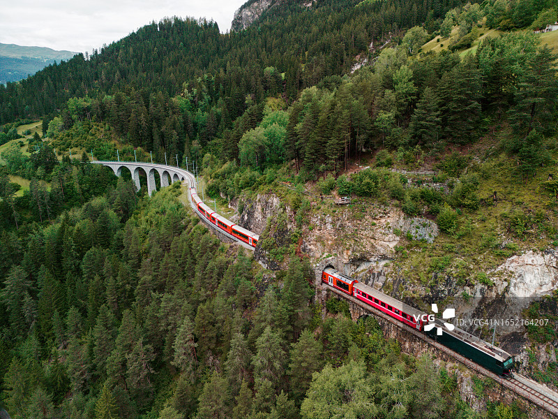 瑞士阿尔卑斯山脉高架桥上的红色列车航拍图片素材