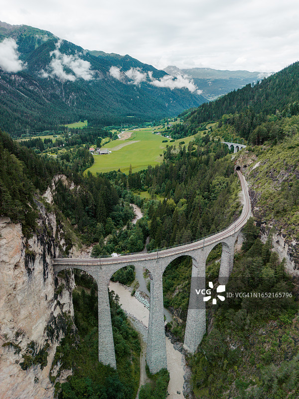 瑞士阿尔卑斯山脉高架桥上的红色列车航拍图片素材