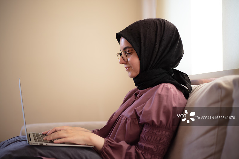 戴着头巾的年轻女子在笔记本电脑上进行网上购物图片素材
