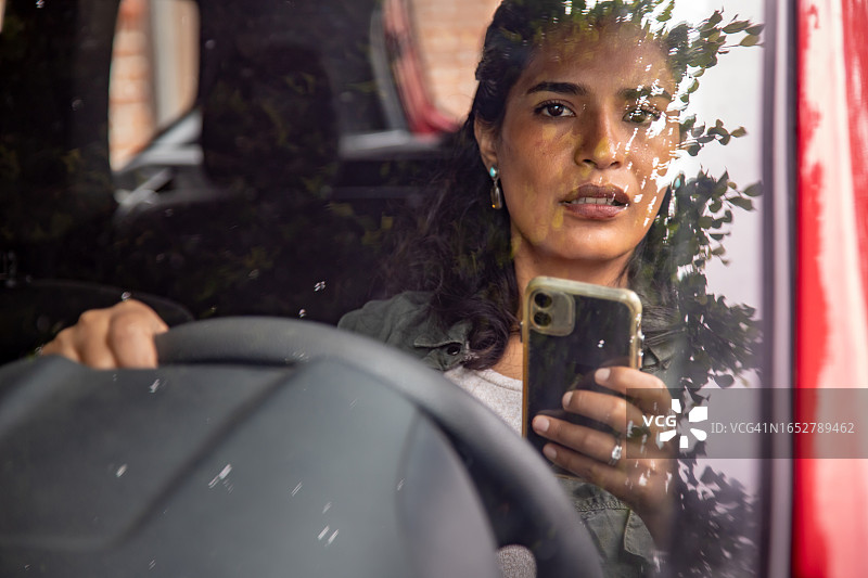 分心驾驶概念：驾驶时使用智能手机的女人图片素材