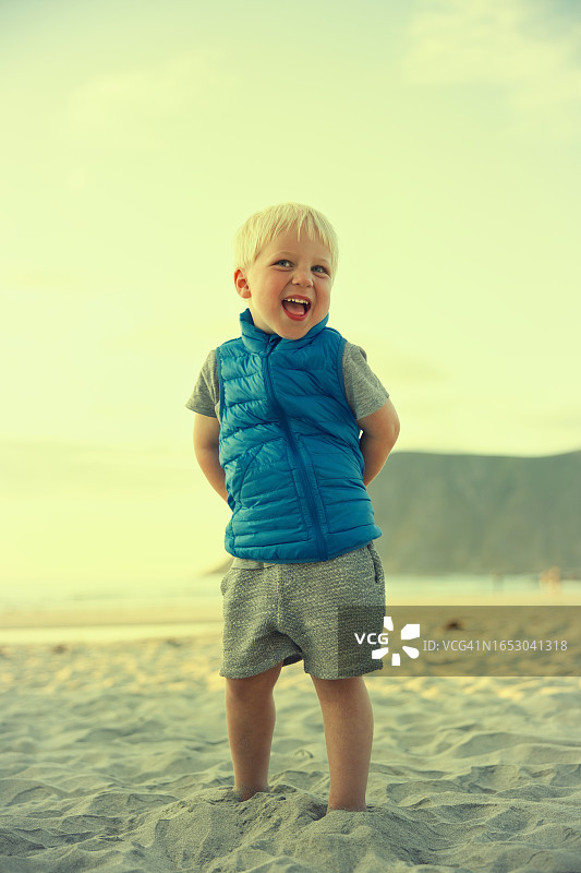 在海滩上微笑的穿蓝色背心的男孩图片素材