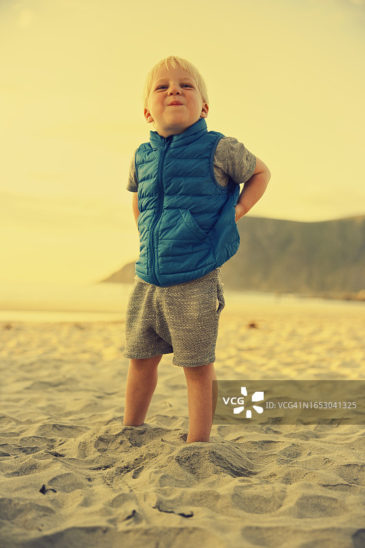 在海滩上微笑的穿蓝色背心的男孩图片素材