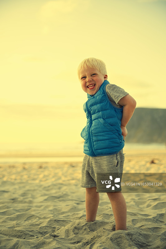 在海滩上微笑的穿蓝色背心的男孩图片素材