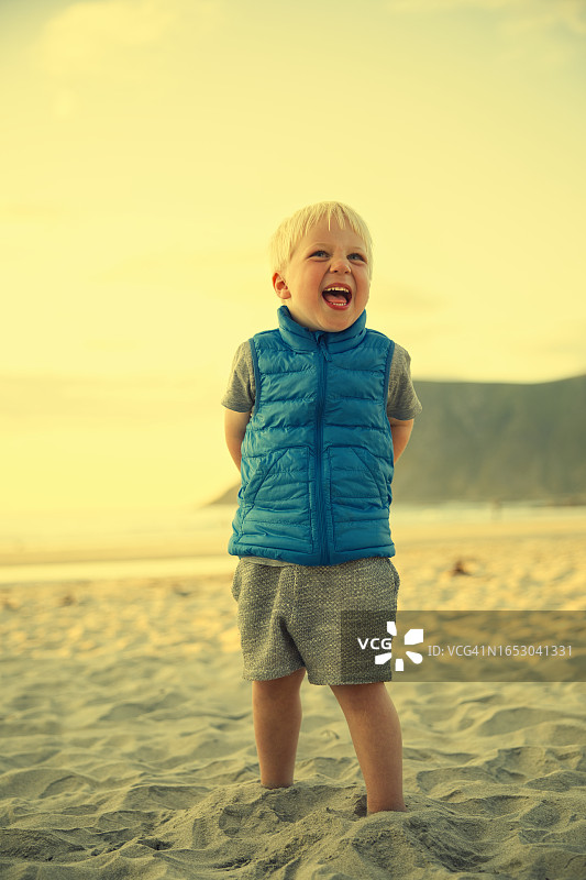在海滩上微笑的穿蓝色背心的男孩图片素材