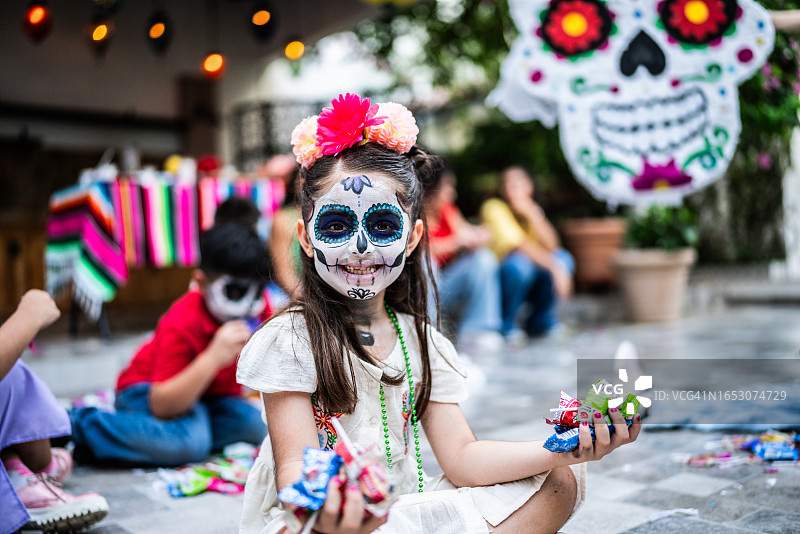 亡灵节庆祝活动中，女孩捡糖果的肖像图片素材