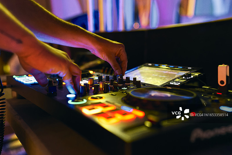 DJ在夜间活动中调节混音台音乐的特写图片素材