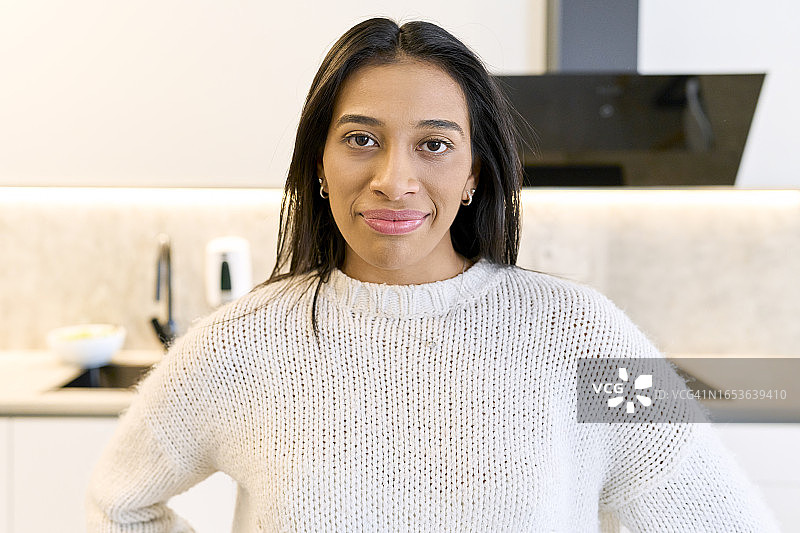 穿着针织毛衣的现代女性站在美丽公寓的厨房里图片素材